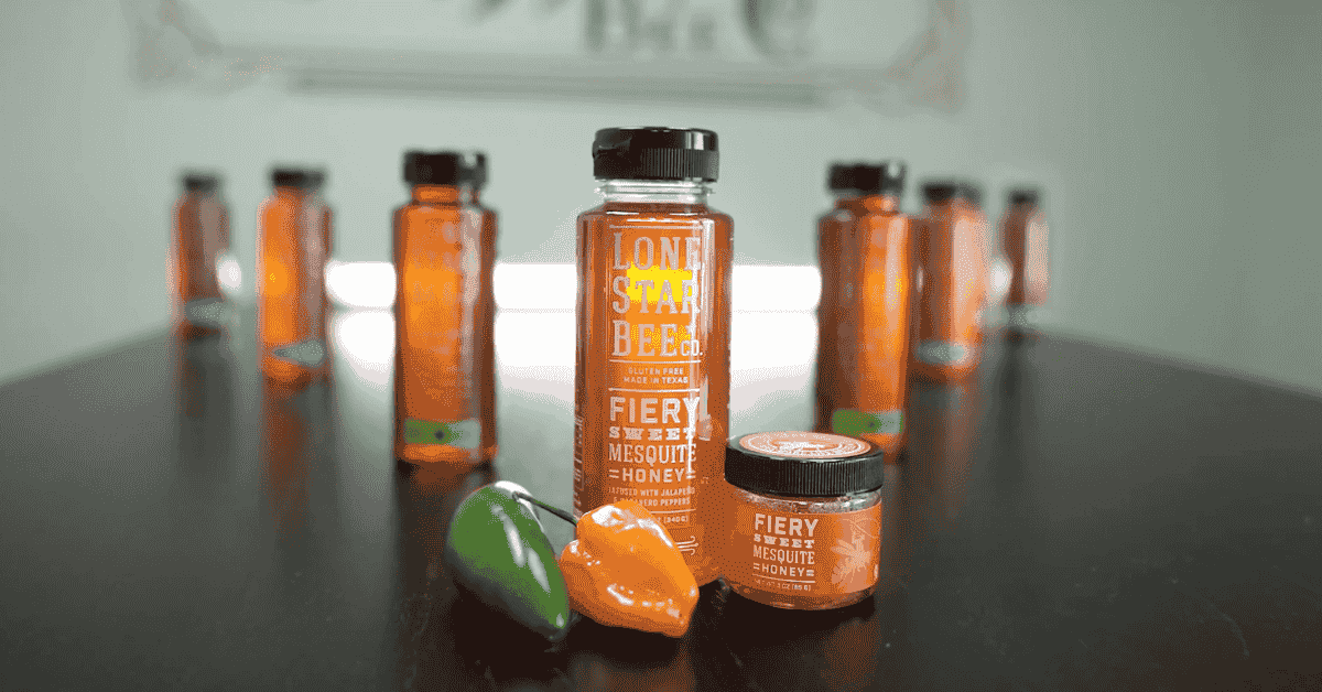 ssorted Lone Star Bee Co. honey jars with oranges on a wooden surface