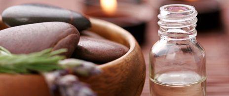 Open amber and clear essential oil bottles on a wooden surface with herbs