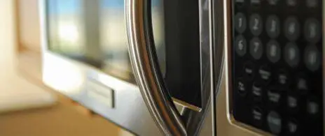 Person placing plastic container into a microwave oven